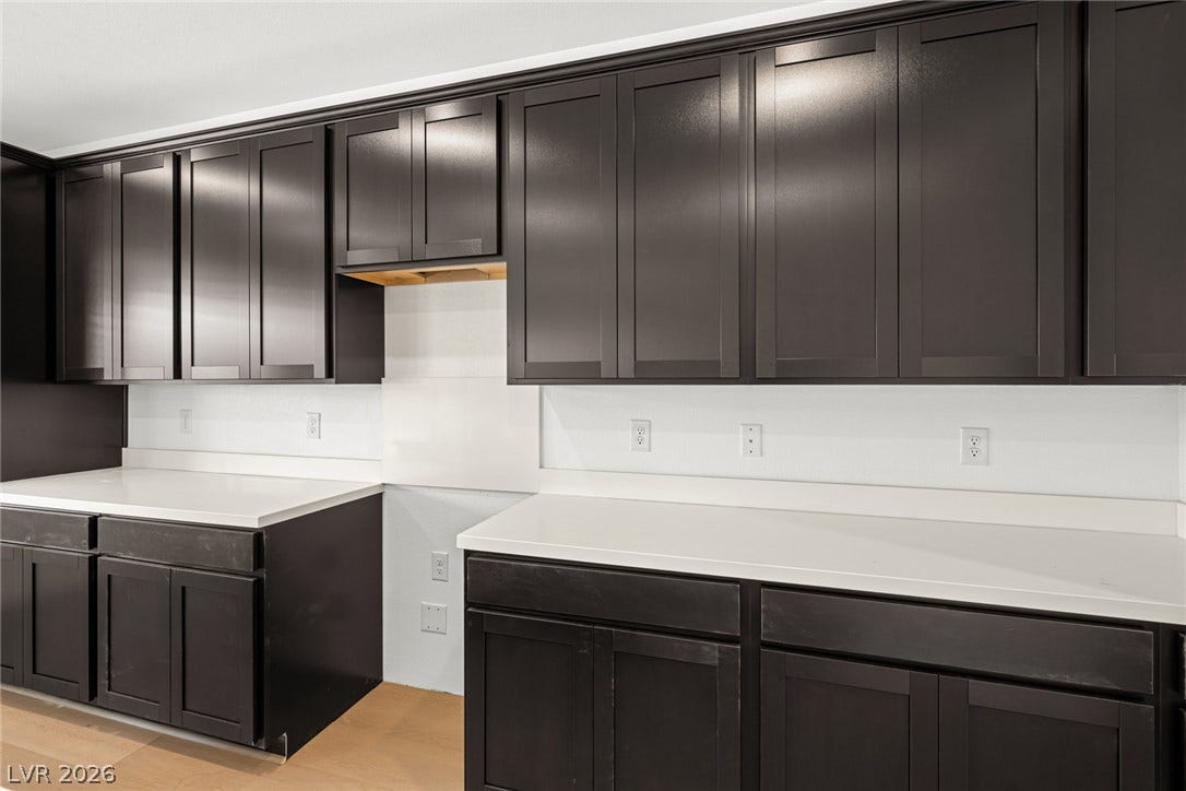 11823 Mimicking Song Lane, Las Vegas, NV 89138 Sleek dark cabinetry contrasts beautifully with pristine white countertops in this modern kitchen design.