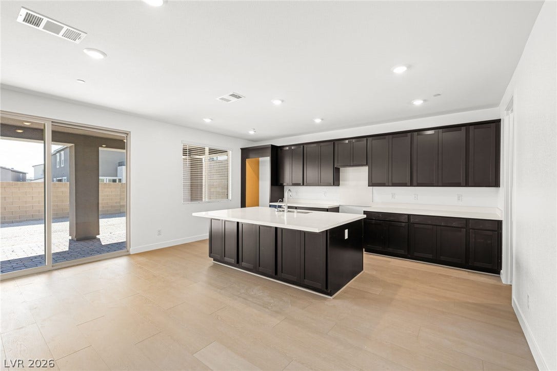 11823 Mimicking Song Lane, Las Vegas, NV 89138 Crisp white walls contrast with dark cabinetry in a spacious kitchen featuring a central island.