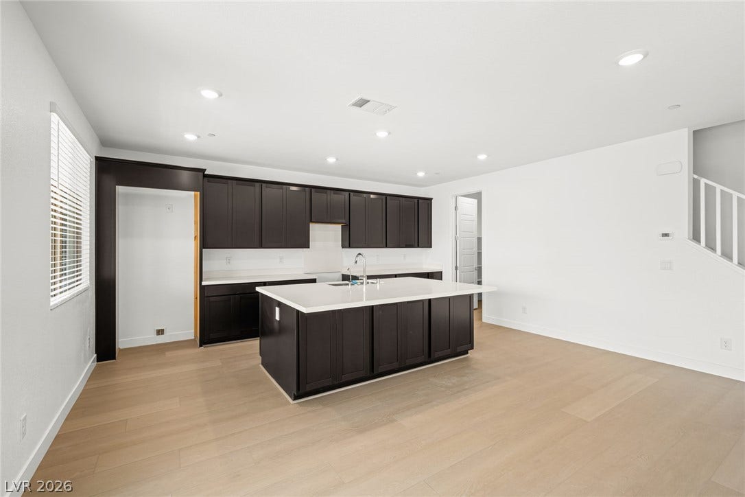11823 Mimicking Song Lane, Las Vegas, NV 89138 Crisp white walls contrast with dark cabinetry and light wood flooring in this open kitchen.