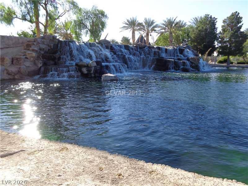 1874 Nature Park Drive, North Las Vegas, NV 89084 Cascading rock waterfalls spill into a tranquil pond surrounded by lush palms and mature trees.