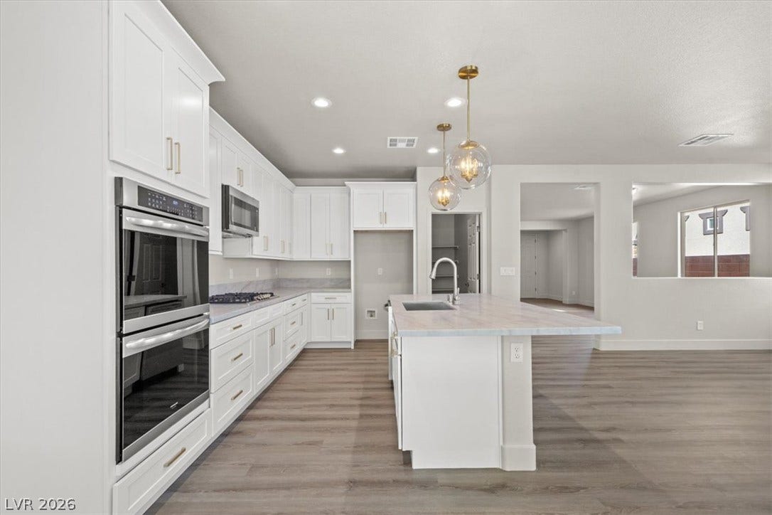 1874 Nature Park Drive, North Las Vegas, NV 89084 Gleaming wood floors anchor this open kitchen featuring a central island and stone counters.