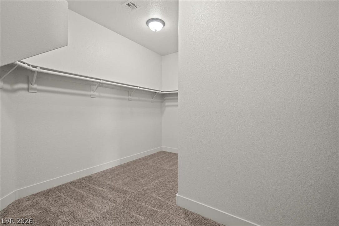 1874 Nature Park Drive, North Las Vegas, NV 89084 An organized walk-in closet boasts neutral carpeting and built-in hanging rods.