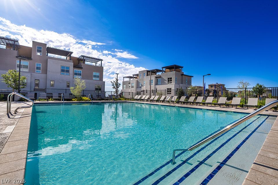 655 Talon Ridge Street, Las Vegas, NV 89138 Modern multi-level townhomes border a sparkling community pool under clear blue skies.