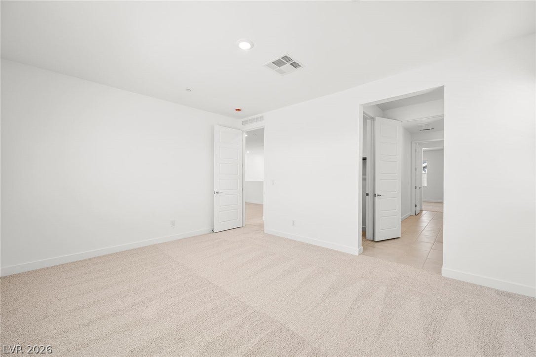 A spacious room offers plush carpeting and a clean, neutral palette.