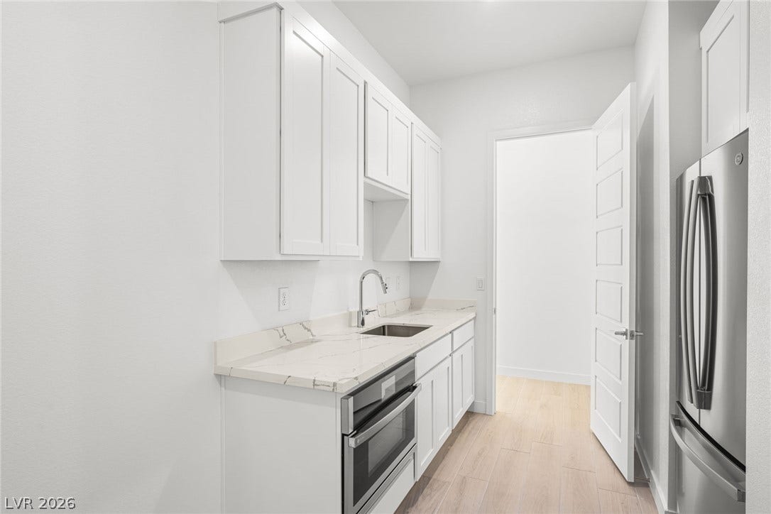 White cabinetry, stone counters, and stainless steel appliances adorn this efficient culinary space.