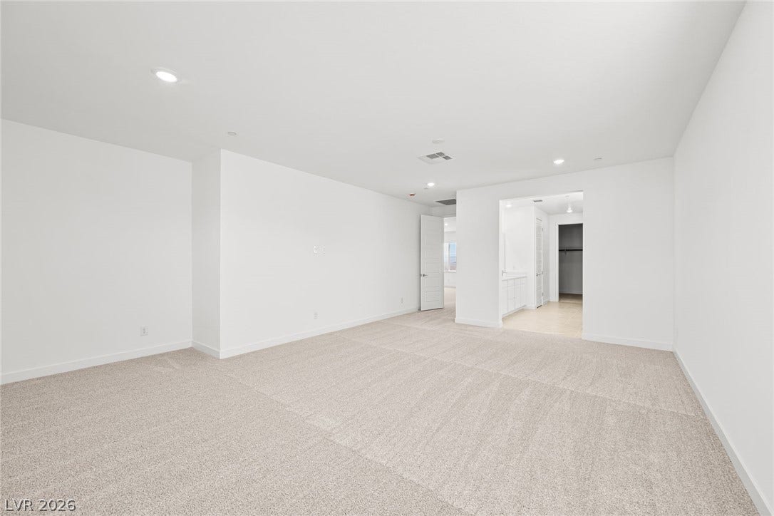 An airy, well-lit room features soft carpet flooring and recessed lighting.