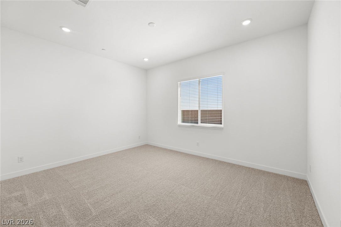 A well-lit room with recessed lighting and neutral carpeting awaits your personal touch.