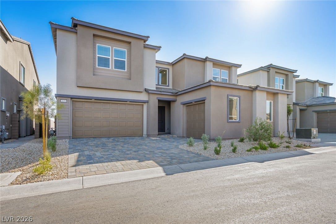 A contemporary facade with clean lines and a paver driveway offers a welcoming entrance to this modern residence.