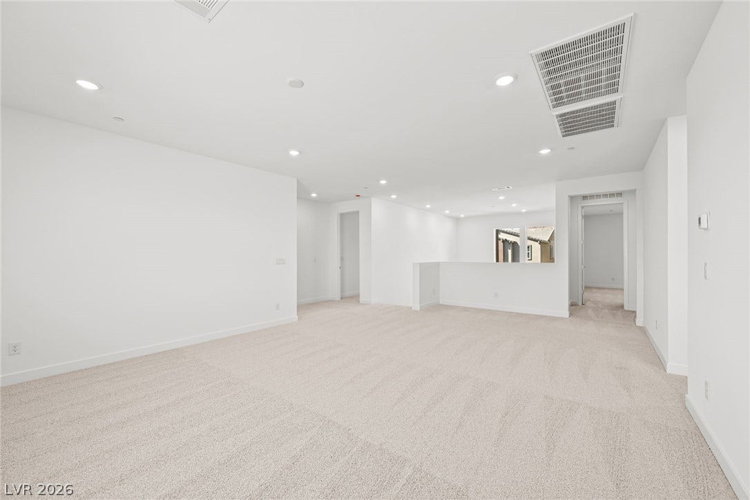 A spacious, naturally illuminated loft provides versatile living space with plush carpeting and modern recessed lighting.