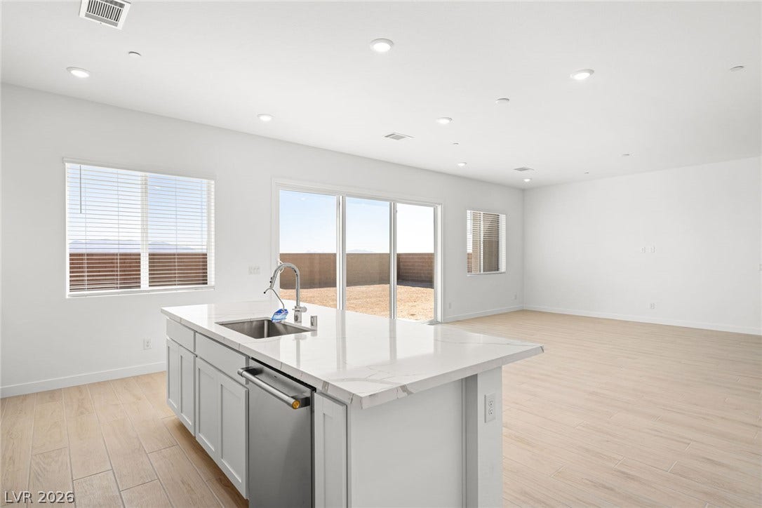 A well-lit interior features a central island with a sink and ample counter space, adjacent to large sliding glass doors leading to the exterior.
