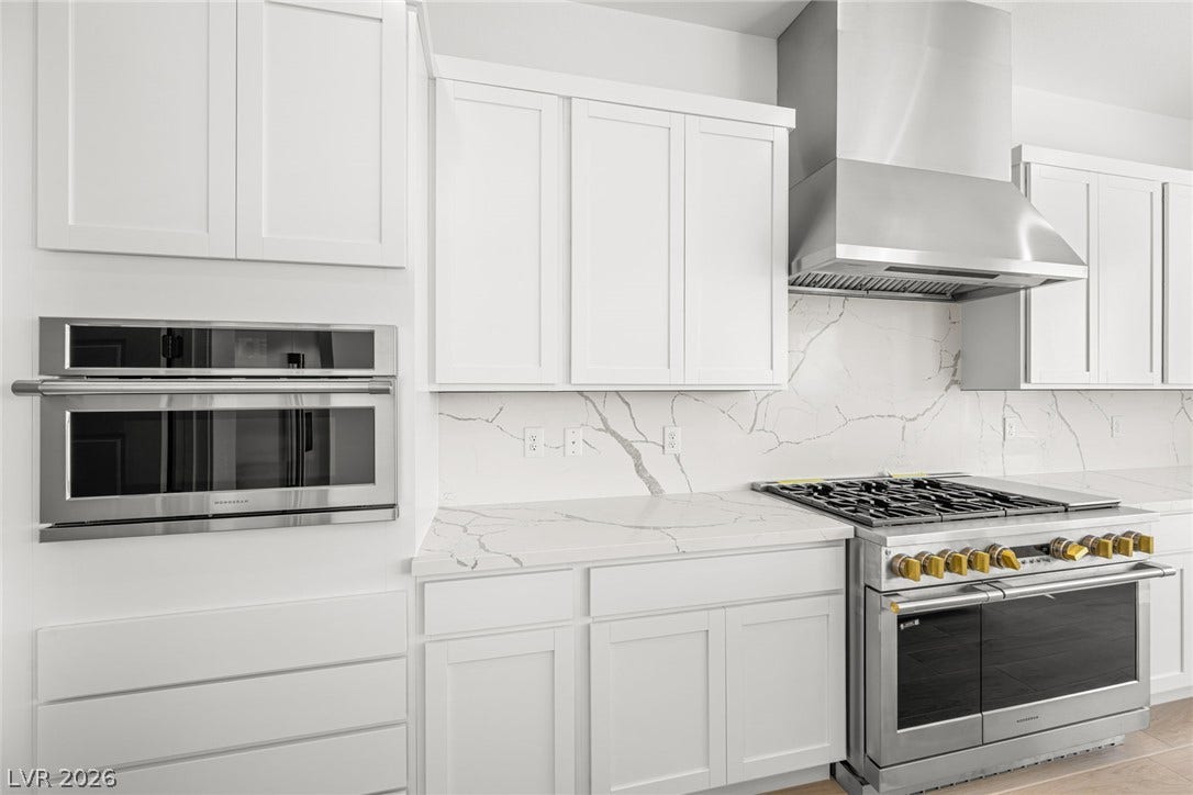 A contemporary kitchen showcasing crisp white cabinetry and elegant marble-patterned countertops with modern stainless steel appliances.