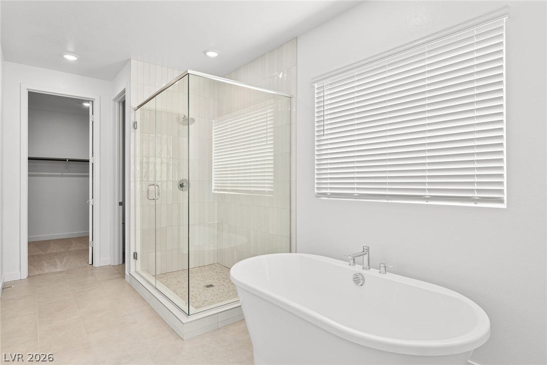 Indulge in this tranquil bathroom, featuring a glass-enclosed shower and a freestanding soaking tub.