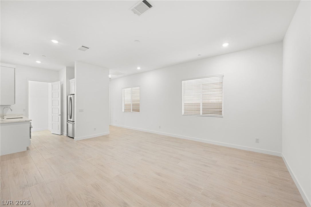Clean lines and a luminous atmosphere define this expansive living area, flowing seamlessly into a modern kitchen.
