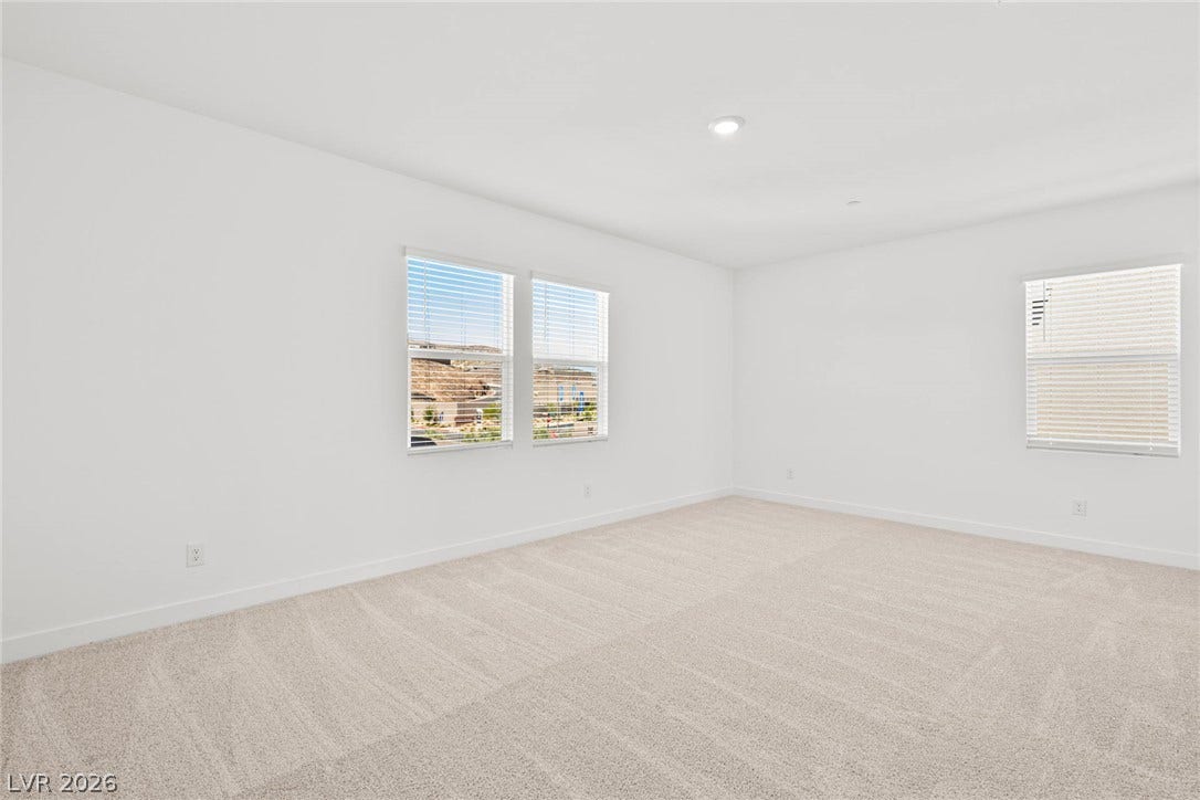 A spacious, naturally illuminated room featuring plush carpeting and multiple windows.