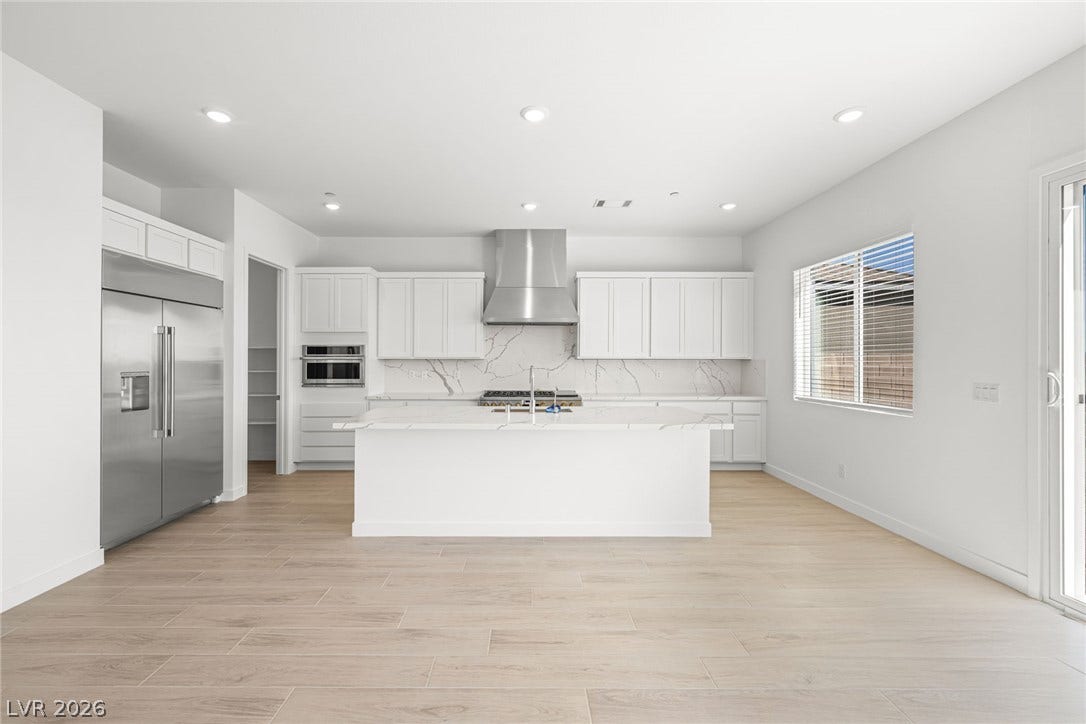 A well-lit, open-concept kitchen features stainless steel appliances, a center island, and wood flooring.