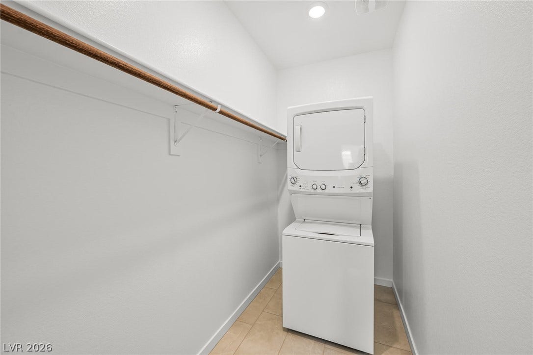 1663 Capri Falls Court, Henderson, NV 89011 A stacked laundry unit sits on tiled flooring beside a long hanging rod.