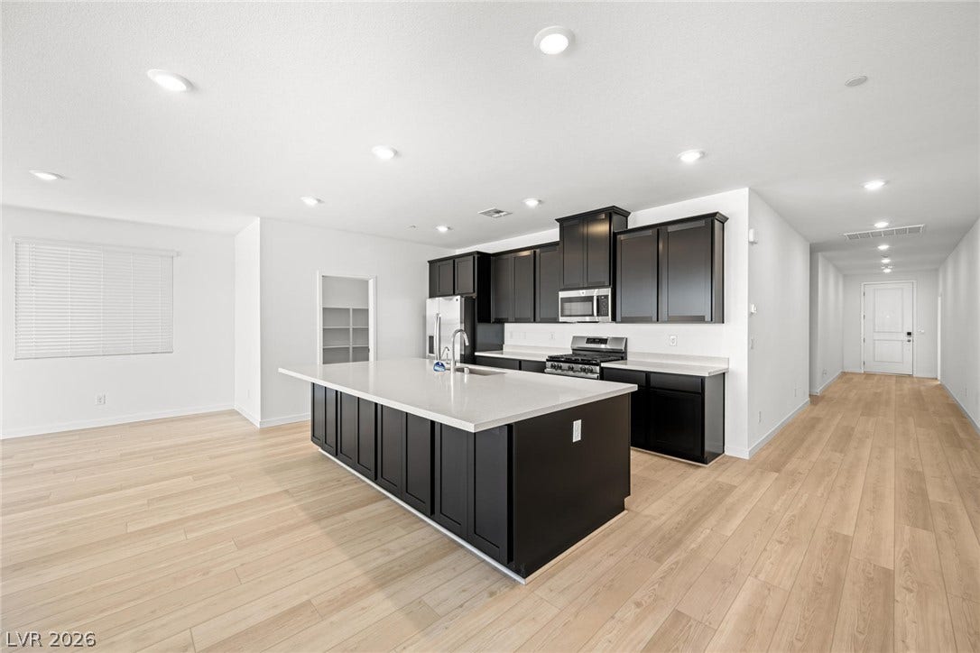 1663 Capri Falls Court, Henderson, NV 89011 Crisp white stone countertops contrast elegantly with dark cabinetry under modern recessed lighting.