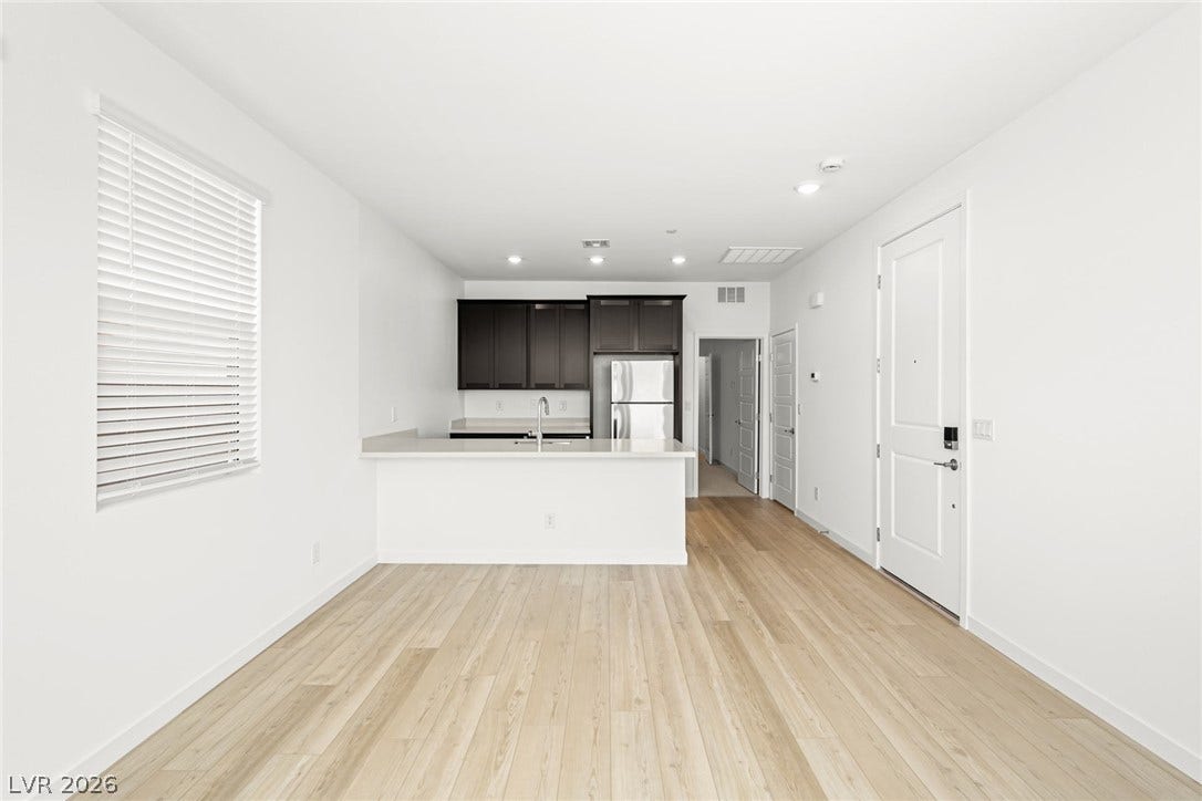 1663 Capri Falls Court, Henderson, NV 89011 Smooth wood floors anchor this open living area connected seamlessly to a modern kitchen.