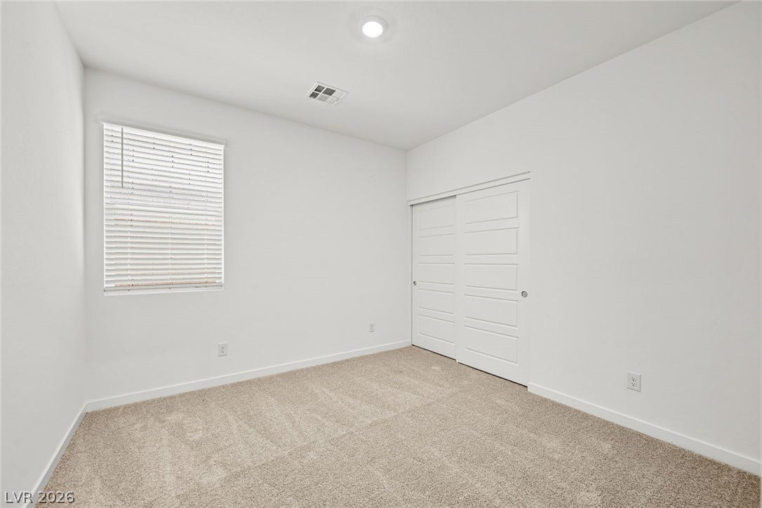 1663 Capri Falls Court, Henderson, NV 89011 A window with built-in blinds illuminates this bedroom featuring plush carpeting and a sliding closet door.