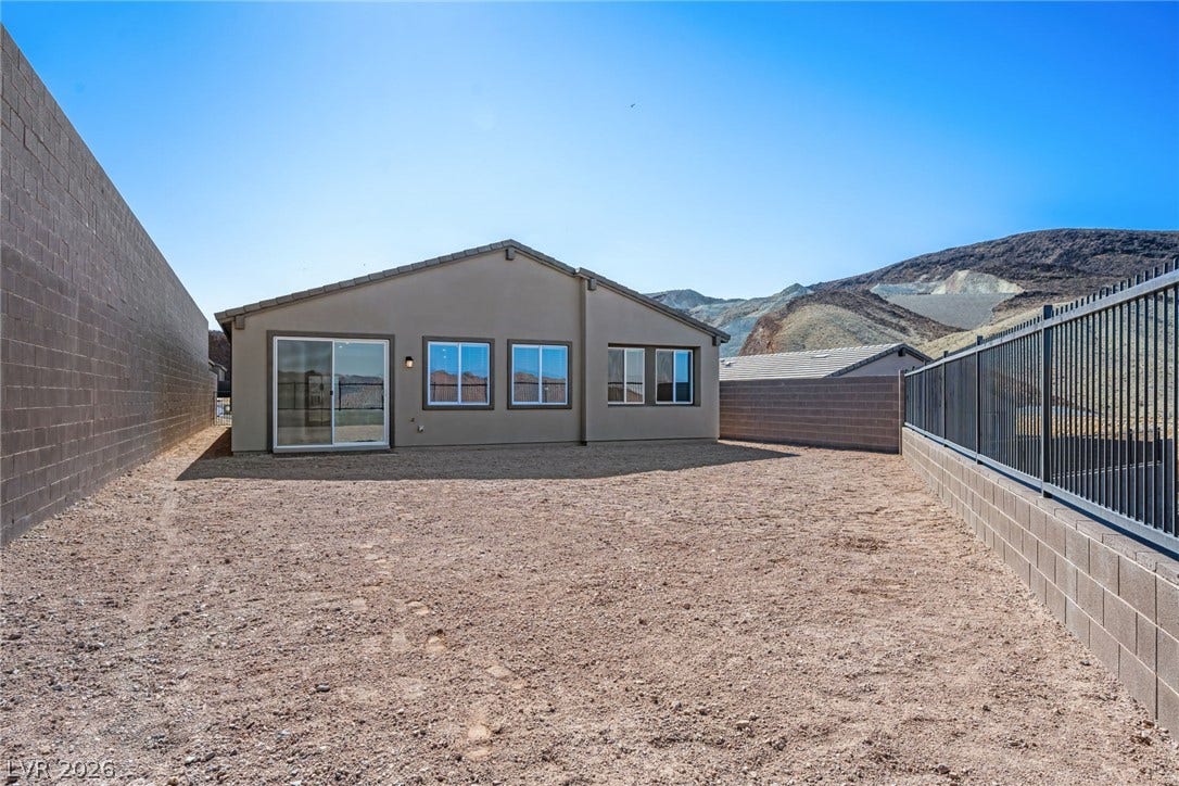 1663 Capri Falls Court, Henderson, NV 89011 An enclosed backyard setting framed by stone walls and metal fencing against scenic hills.