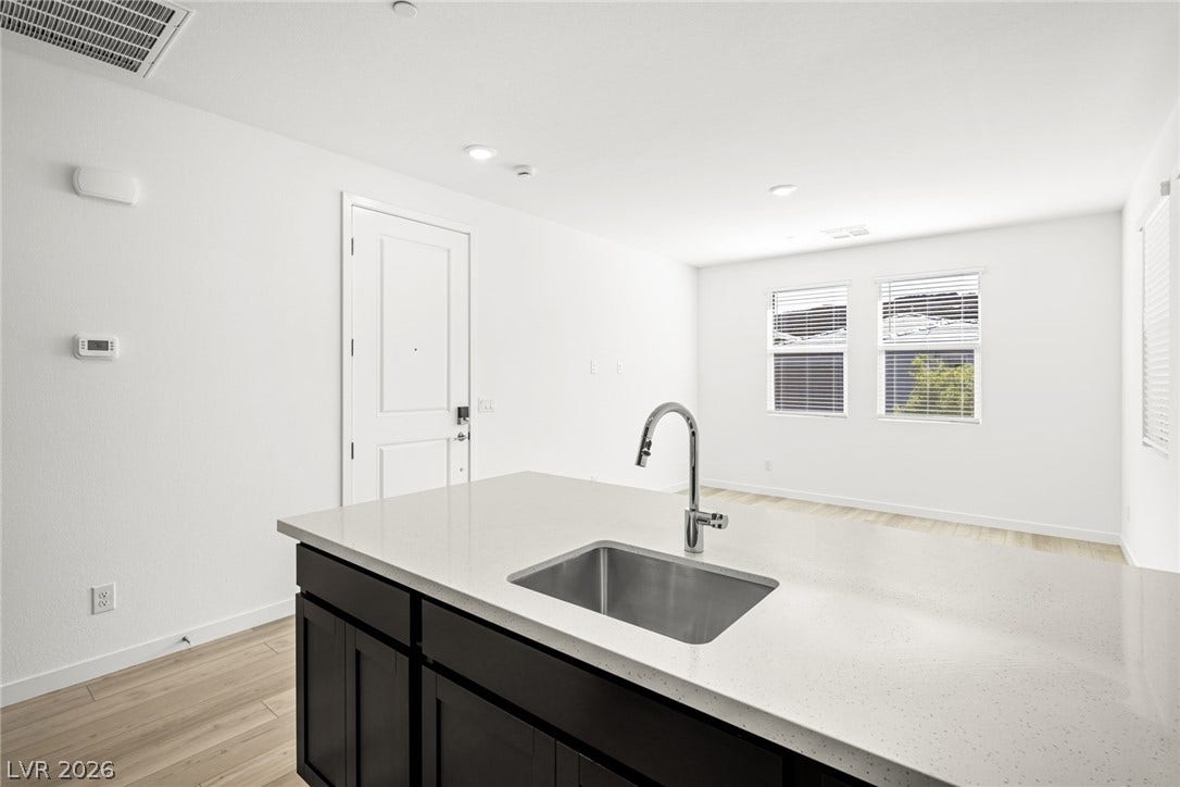 1663 Capri Falls Court, Henderson, NV 89011 Gleaming stone countertops and a modern kitchen island open directly to the airy living space.
