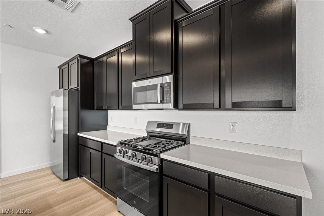1663 Capri Falls Court, Henderson, NV 89011 Rich dark cabinetry pairs beautifully with sleek stone countertops in this modern cooking space.