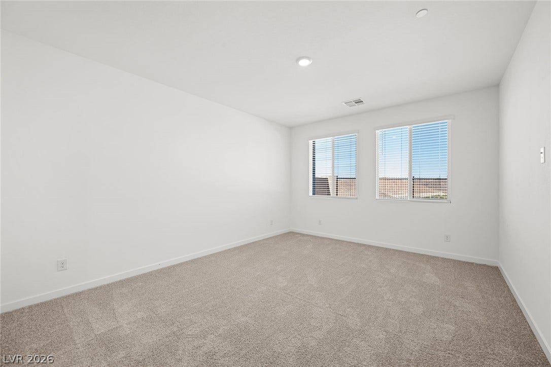 1663 Capri Falls Court, Henderson, NV 89011 Plush carpeting anchors this clean, minimalist bedroom filled with natural light from dual windows.
