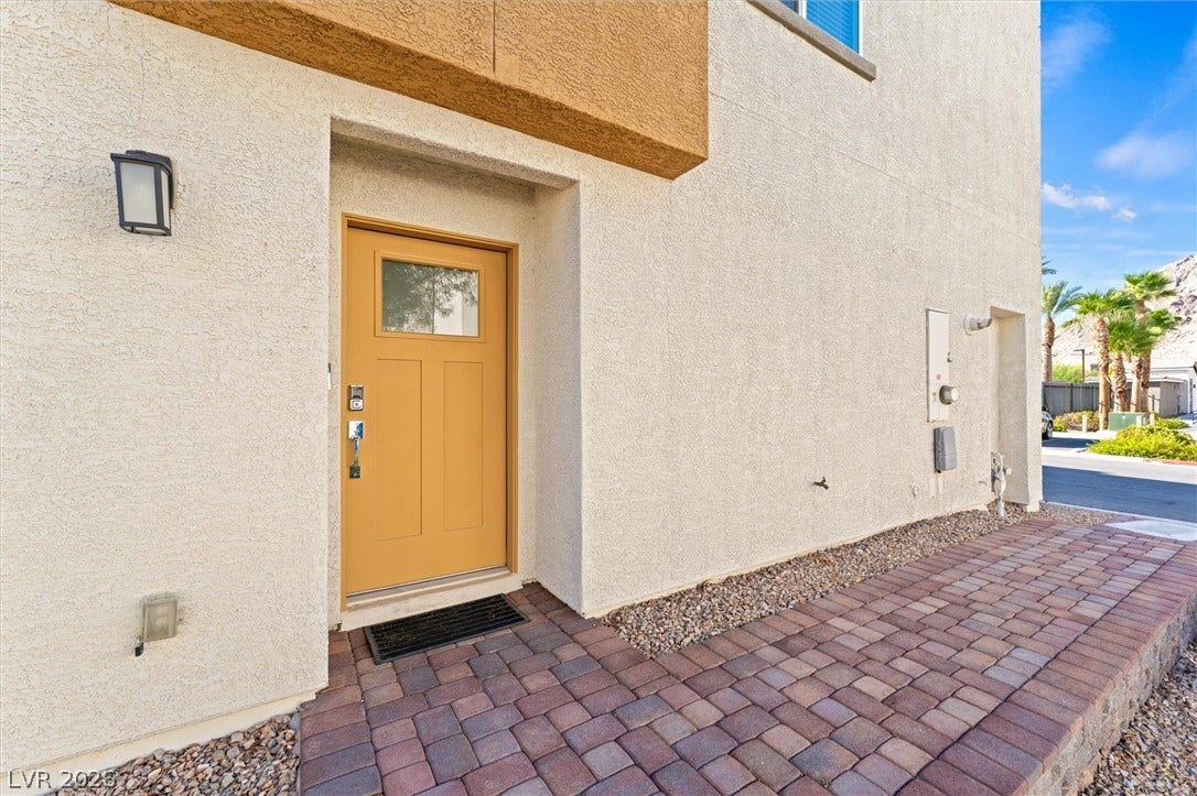 10059 Dazzling Sunrays Avenue, Las Vegas, NV 89129 Clean lines and textured stucco define this modern exterior entryway featuring a warm-toned front door.