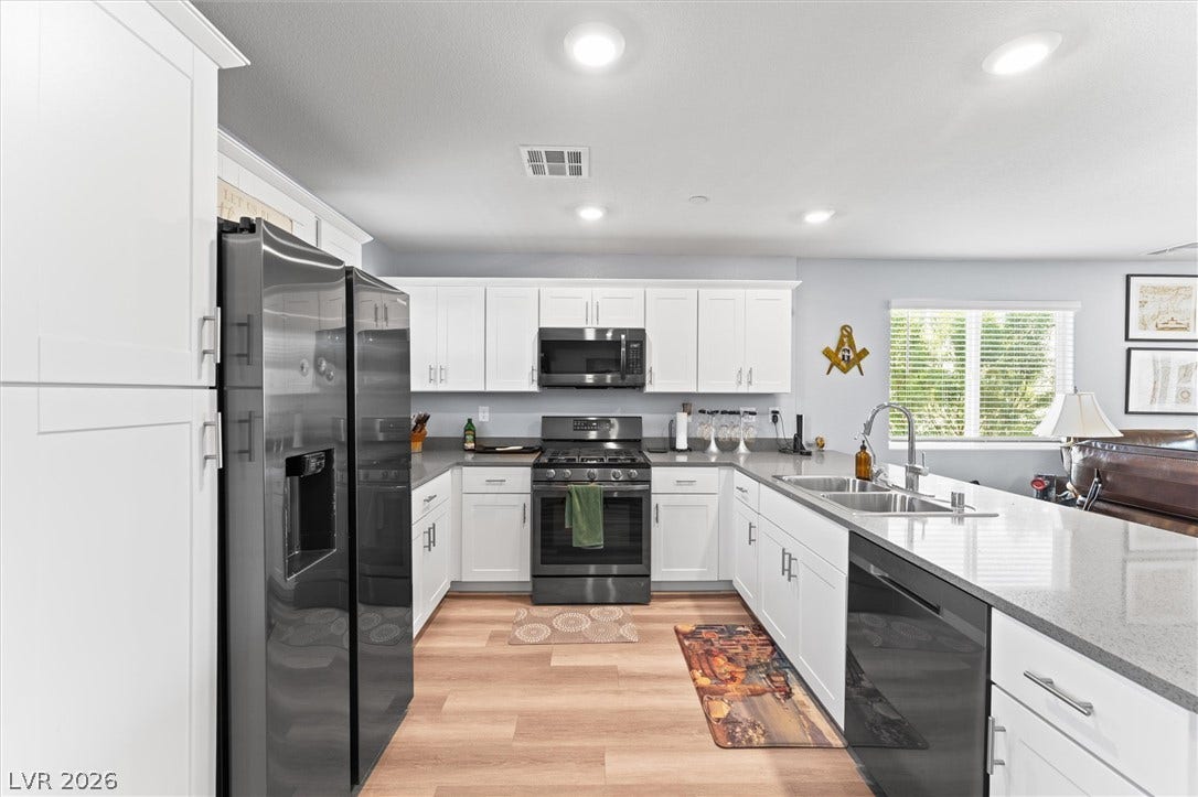 10059 Dazzling Sunrays Avenue, Las Vegas, NV 89129 Modern kitchen features sleek white cabinetry, expansive stone countertops, and stainless steel appliances.
