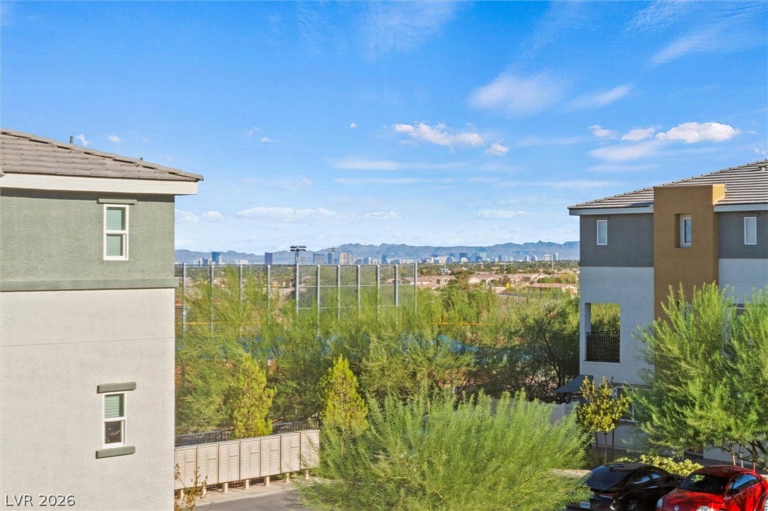 10059 Dazzling Sunrays Avenue, Las Vegas, NV 89129 View from the primary bedroom. Distant mountain ranges and city skylines frame the horizon beyond the surrounding neighborhood.