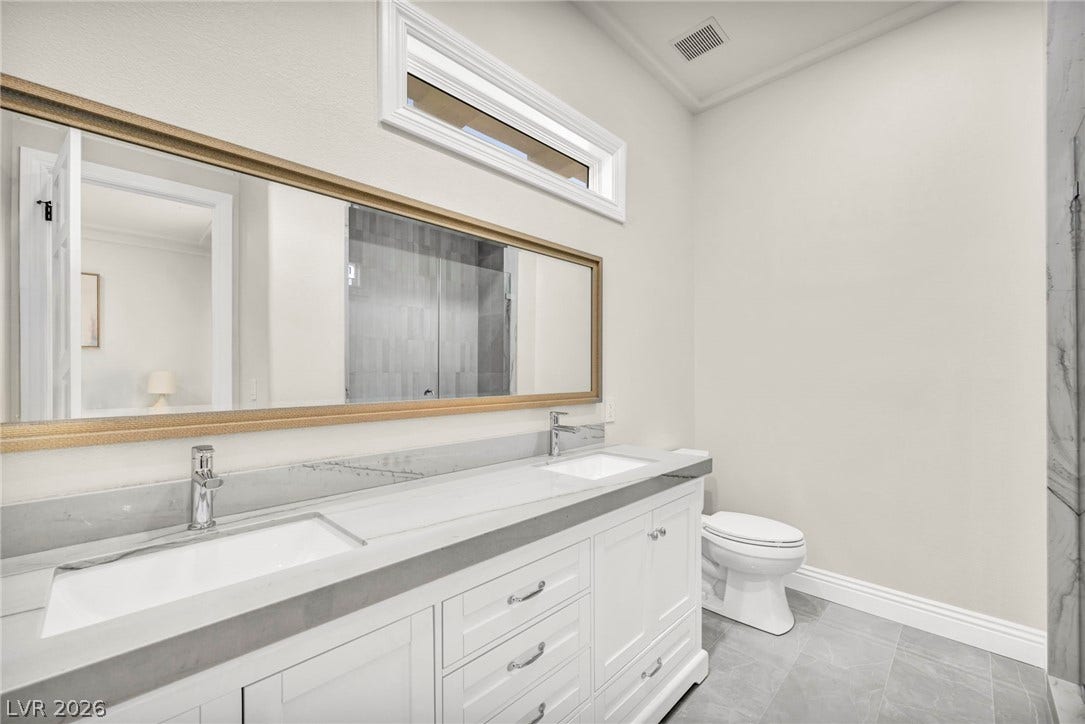 8805 Spanish Mountain Drive, Las Vegas, NV 89148 High ceilings and a wide vanity with stone countertops elevate this contemporary bathroom space.