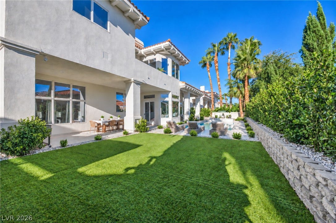 8805 Spanish Mountain Drive, Las Vegas, NV 89148 An manicured lawn leads to a private pool alongside the stucco exterior wall.