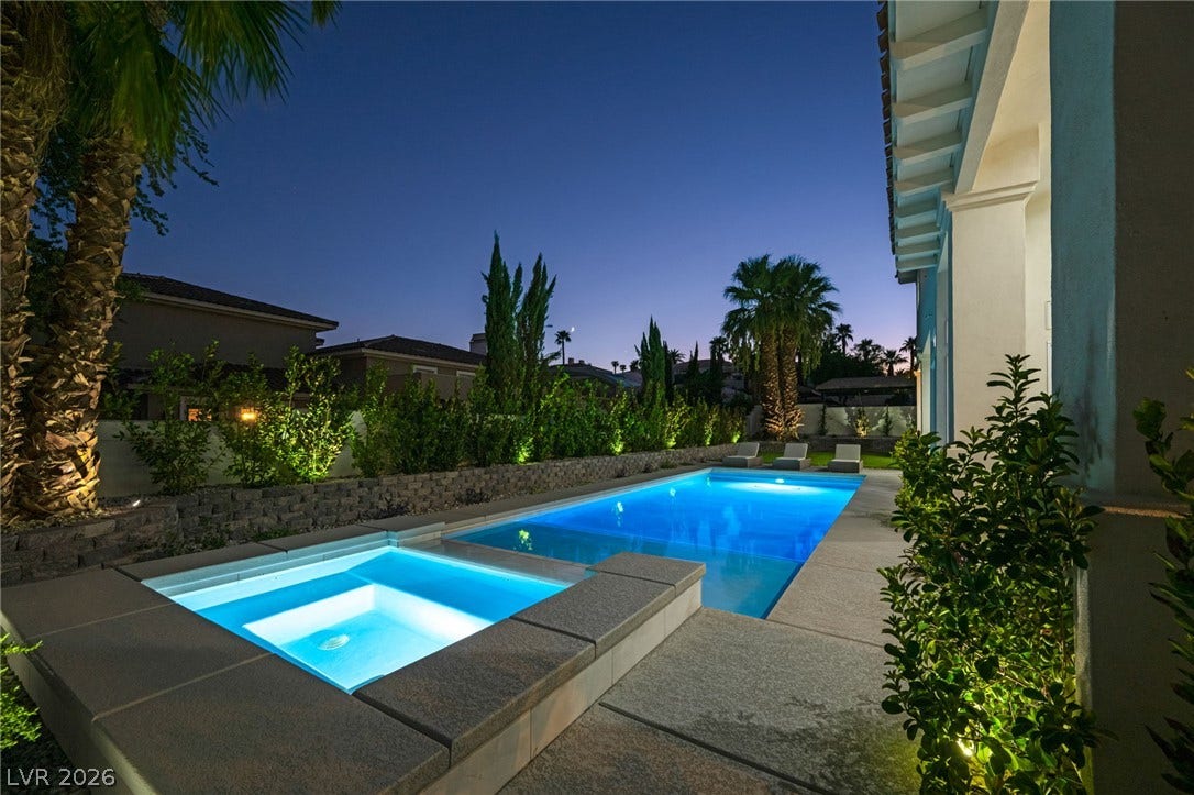 8805 Spanish Mountain Drive, Las Vegas, NV 89148 An inviting swimming pool and integrated spa sit surrounded by manicured landscaping under twilight skies.