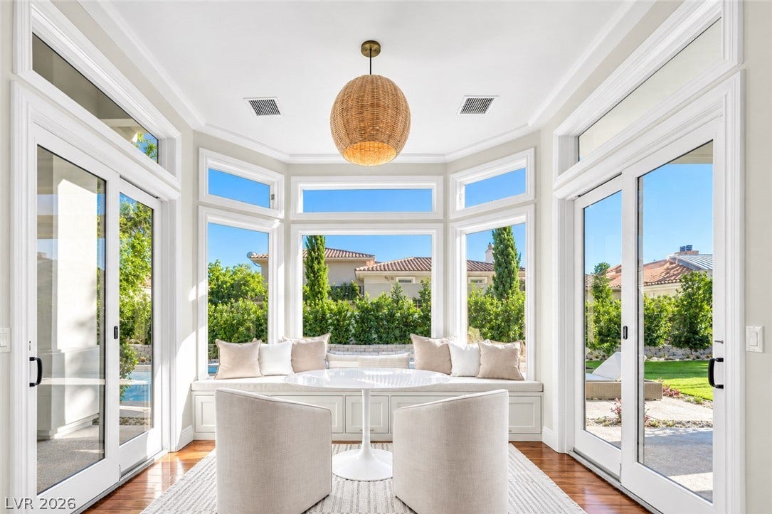 8805 Spanish Mountain Drive, Las Vegas, NV 89148 Sunlight streams through expansive windows highlighting the elegant crown molding and rich hardwood floors.
