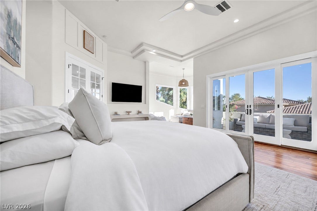 8805 Spanish Mountain Drive, Las Vegas, NV 89148 Rich hardwood floors and elegant tray ceilings define this airy principal bedroom with patio access.