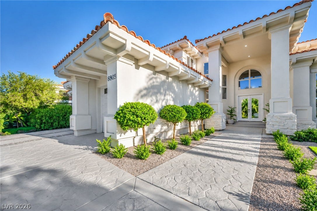 8805 Spanish Mountain Drive, Las Vegas, NV 89148 Spanish tile roofing and grand columns framing a double-door entryway present an elegant exterior.