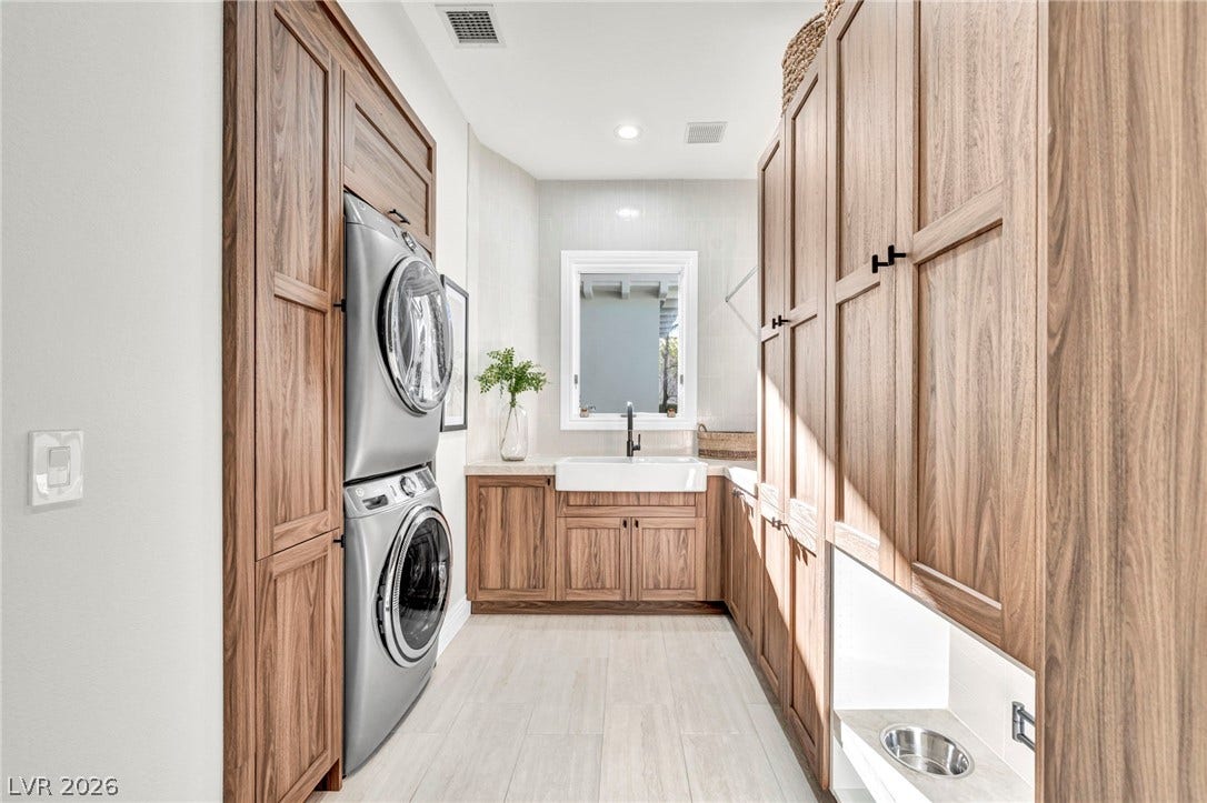 8805 Spanish Mountain Drive, Las Vegas, NV 89148 Rich wood cabinetry surrounds a stacked laundry station and deep utility sink over tile flooring.