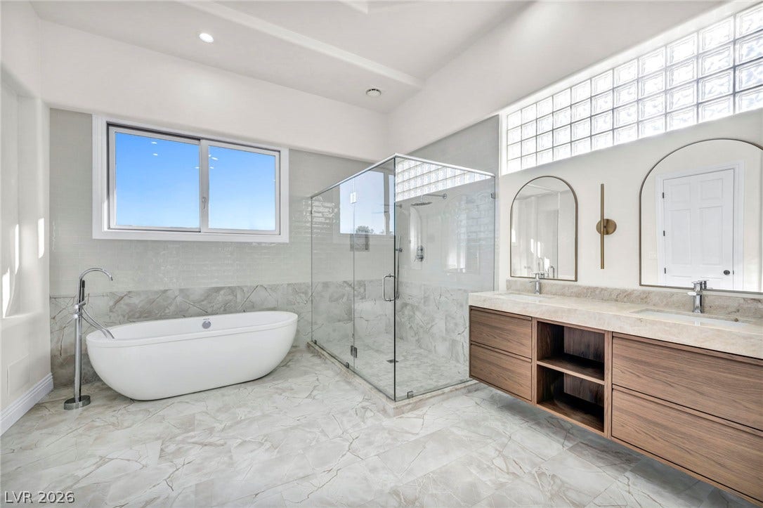 8805 Spanish Mountain Drive, Las Vegas, NV 89148 A glass-enclosed shower, freestanding tub, and floating double vanity highlight this modern primary bath.