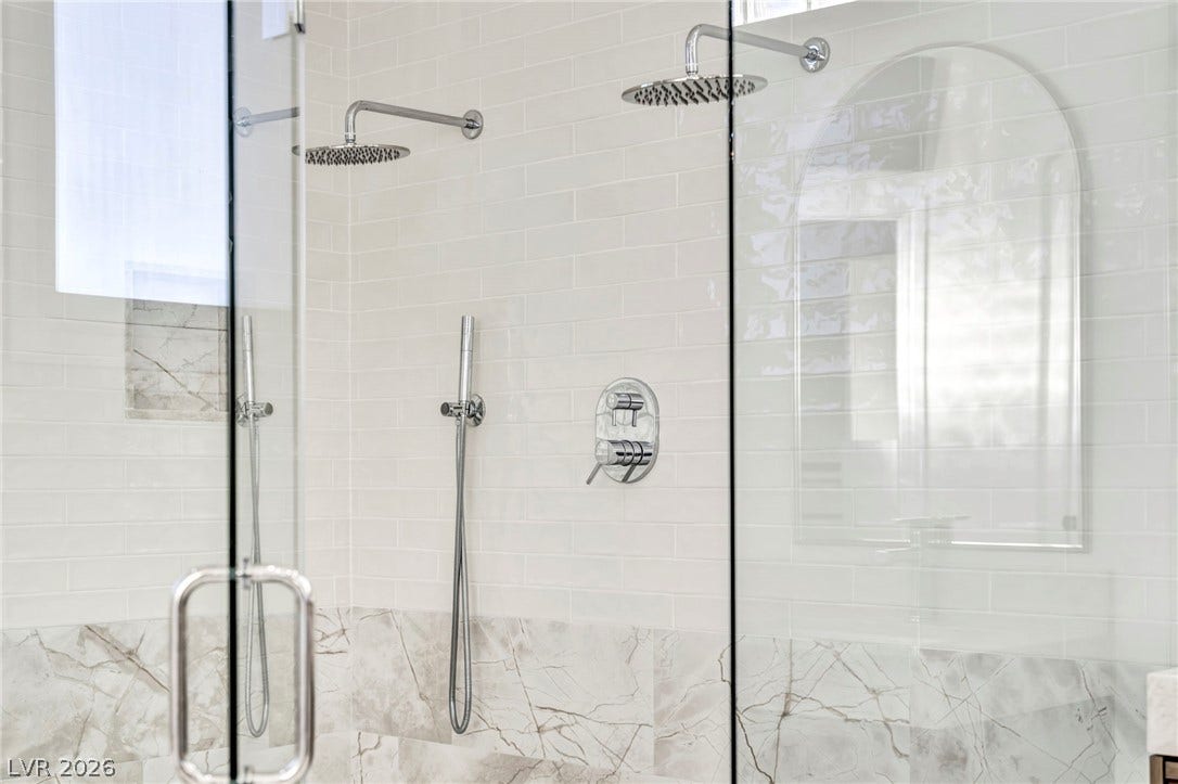 8805 Spanish Mountain Drive, Las Vegas, NV 89148 Gleaming tile walls and dual rainfall showerheads anchor this modern, glass-enclosed walk-in shower.