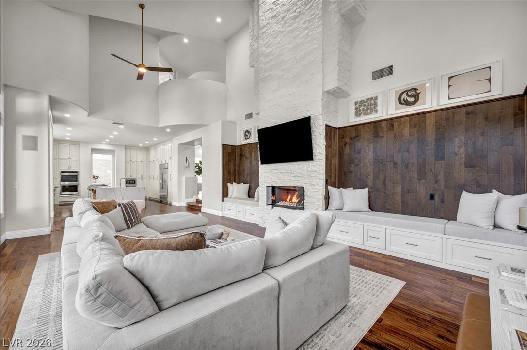8805 Spanish Mountain Drive, Las Vegas, NV 89148 A soaring stone fireplace serves as the centerpiece of this double-height living space with wood floors.