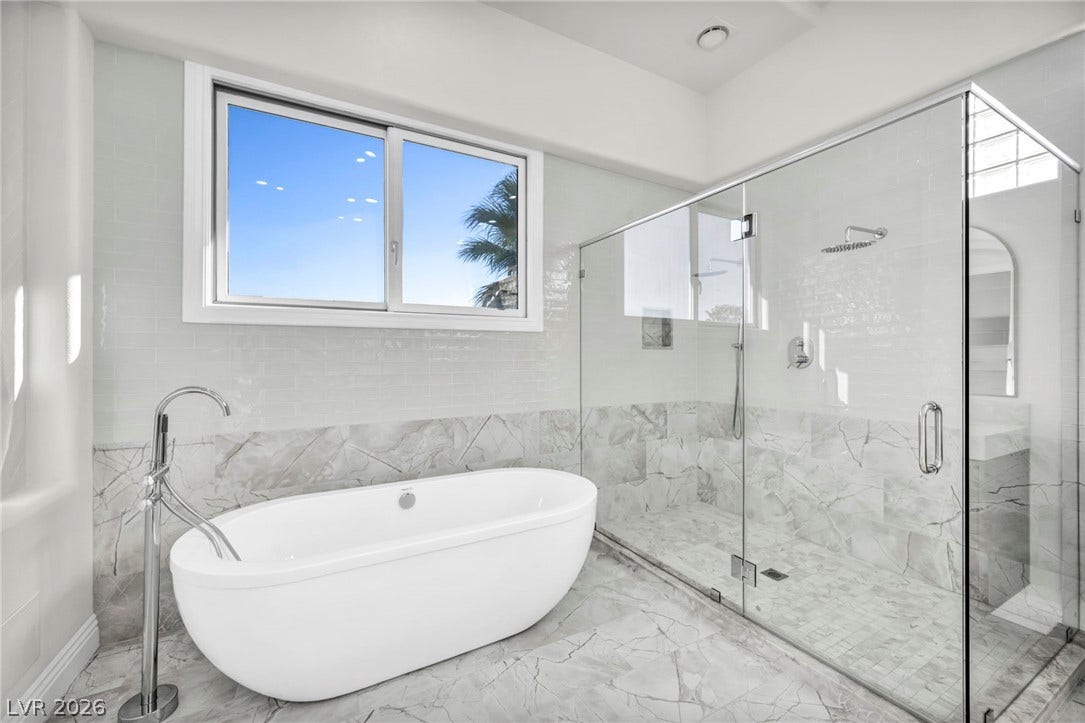 8805 Spanish Mountain Drive, Las Vegas, NV 89148 Marble flooring pairs with a freestanding soaking tub and glass-enclosed shower.