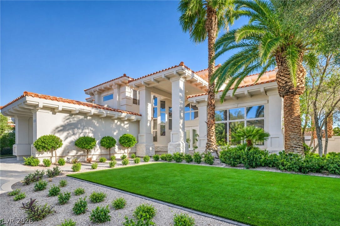 8805 Spanish Mountain Drive, Las Vegas, NV 89148 Spanish tile roofing and grand columns frame this elegant desert estate with manicured landscaping.