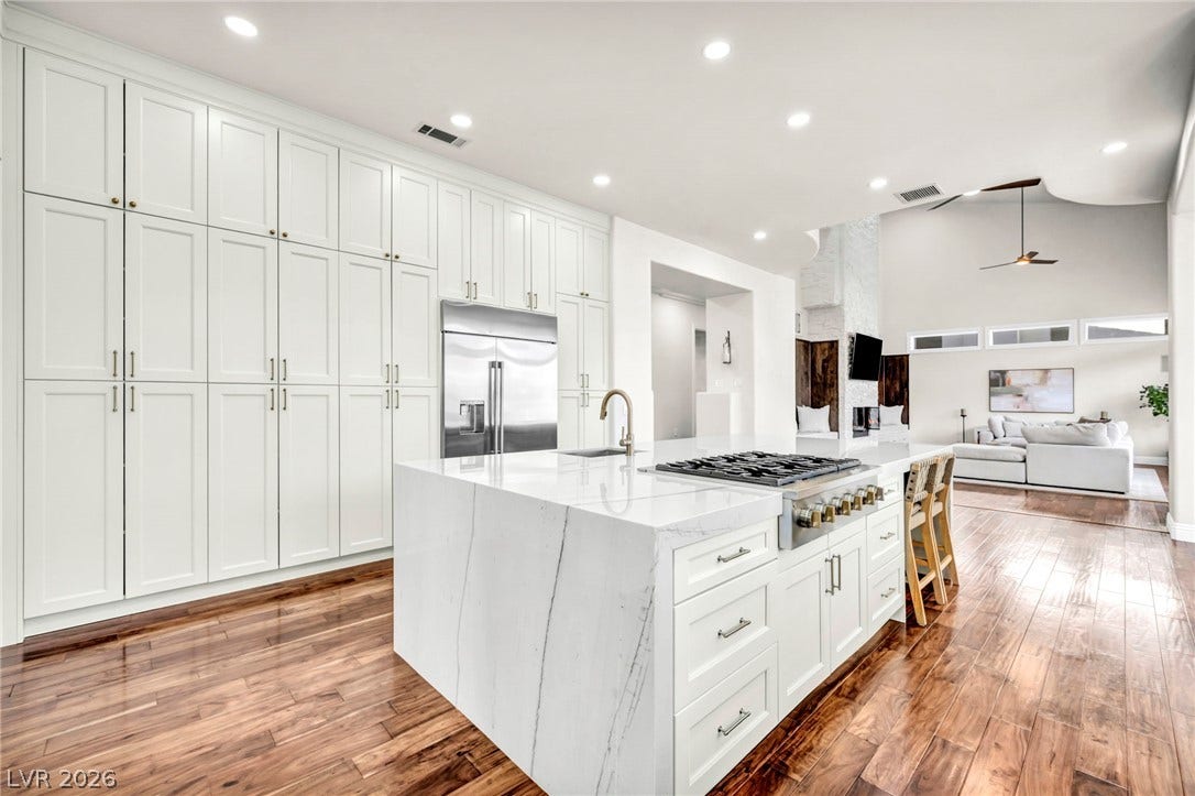 8805 Spanish Mountain Drive, Las Vegas, NV 89148 Polished hardwood flooring runs through this airy kitchen featuring a waterfall marble island and integrated storage.