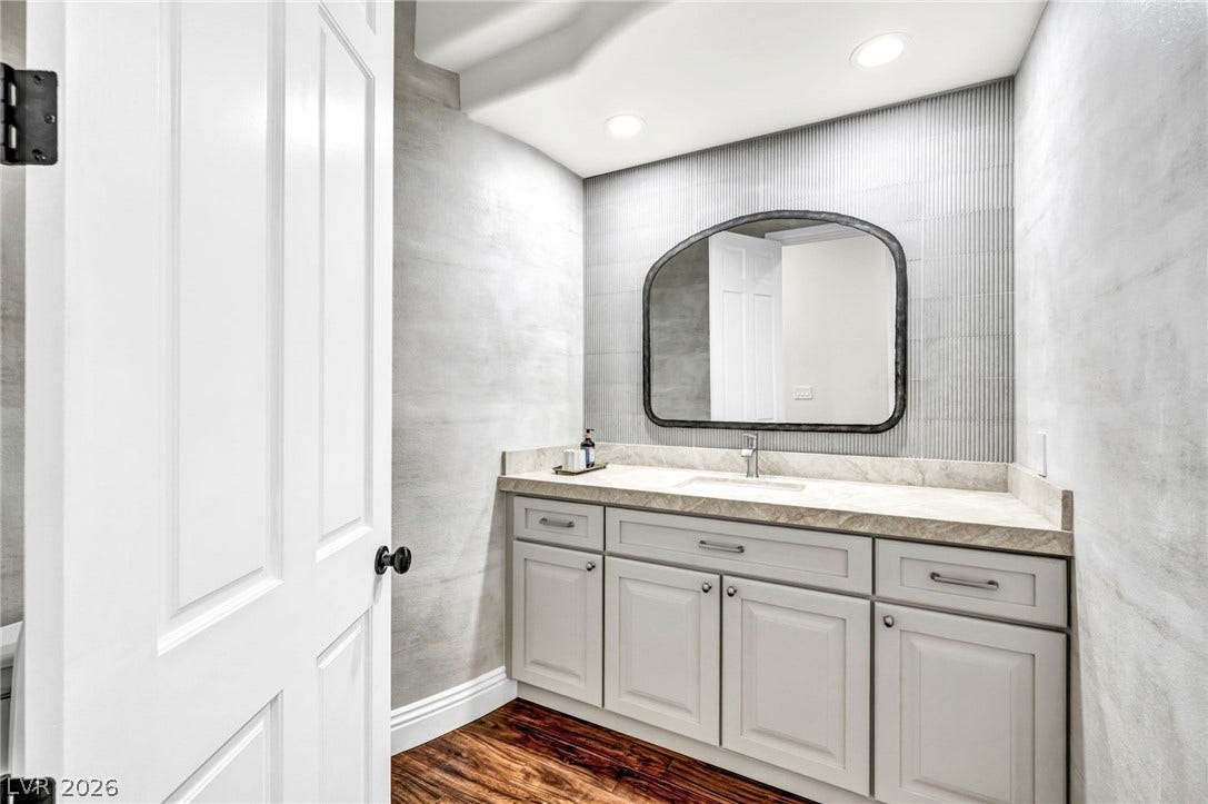 8805 Spanish Mountain Drive, Las Vegas, NV 89148 Rich hardwood flooring complements the modern vanity and textured wall details in this half bath.