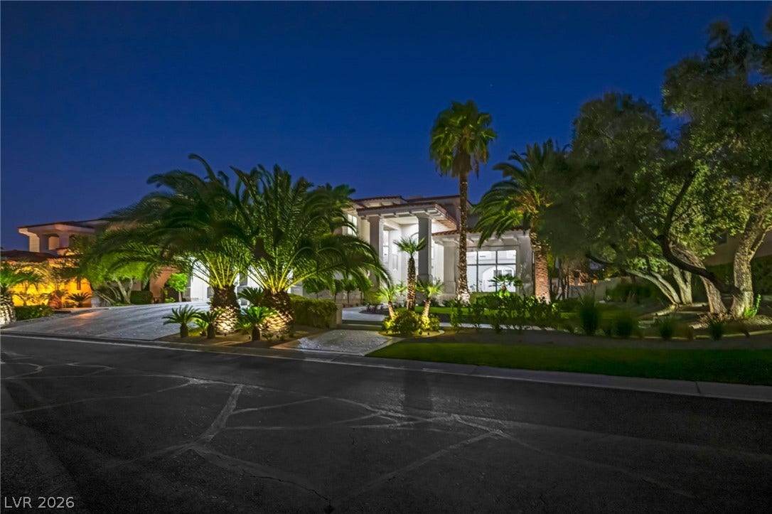 8805 Spanish Mountain Drive, Las Vegas, NV 89148 Dramatic up-lighting illuminates towering palm trees and manicured landscaping across a sprawling desert estate.