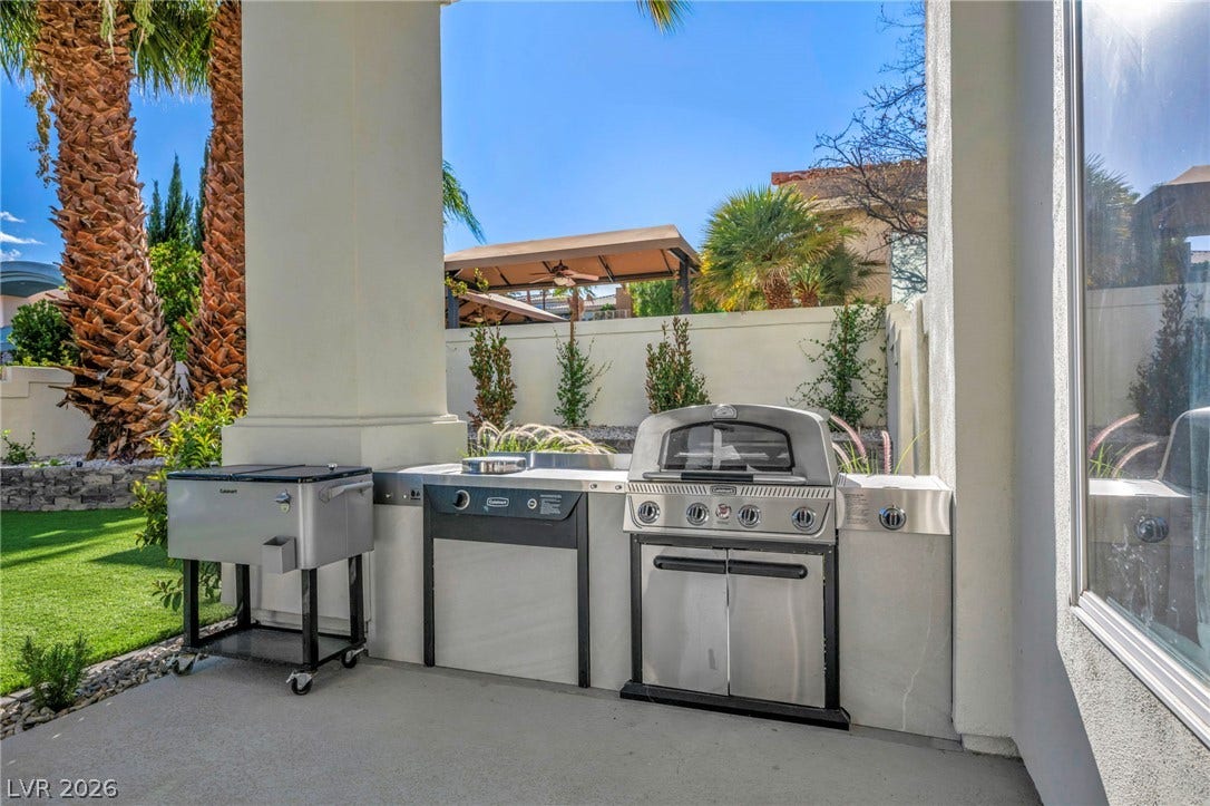 8805 Spanish Mountain Drive, Las Vegas, NV 89148 A built-in grilling station sits under a sheltered patio overlooking a landscaped yard.