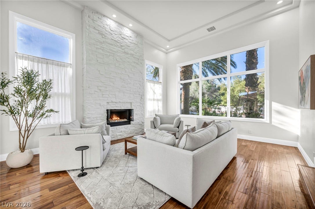 8805 Spanish Mountain Drive, Las Vegas, NV 89148 Towering windows and a dramatic stone fireplace frame this light-filled room with polished hardwood floors.