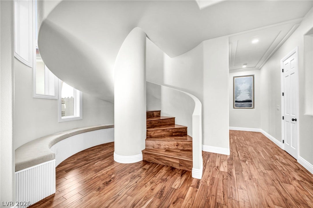 8805 Spanish Mountain Drive, Las Vegas, NV 89148 A sculptural spiral staircase and rich wood flooring anchor this architectural entry hallway.