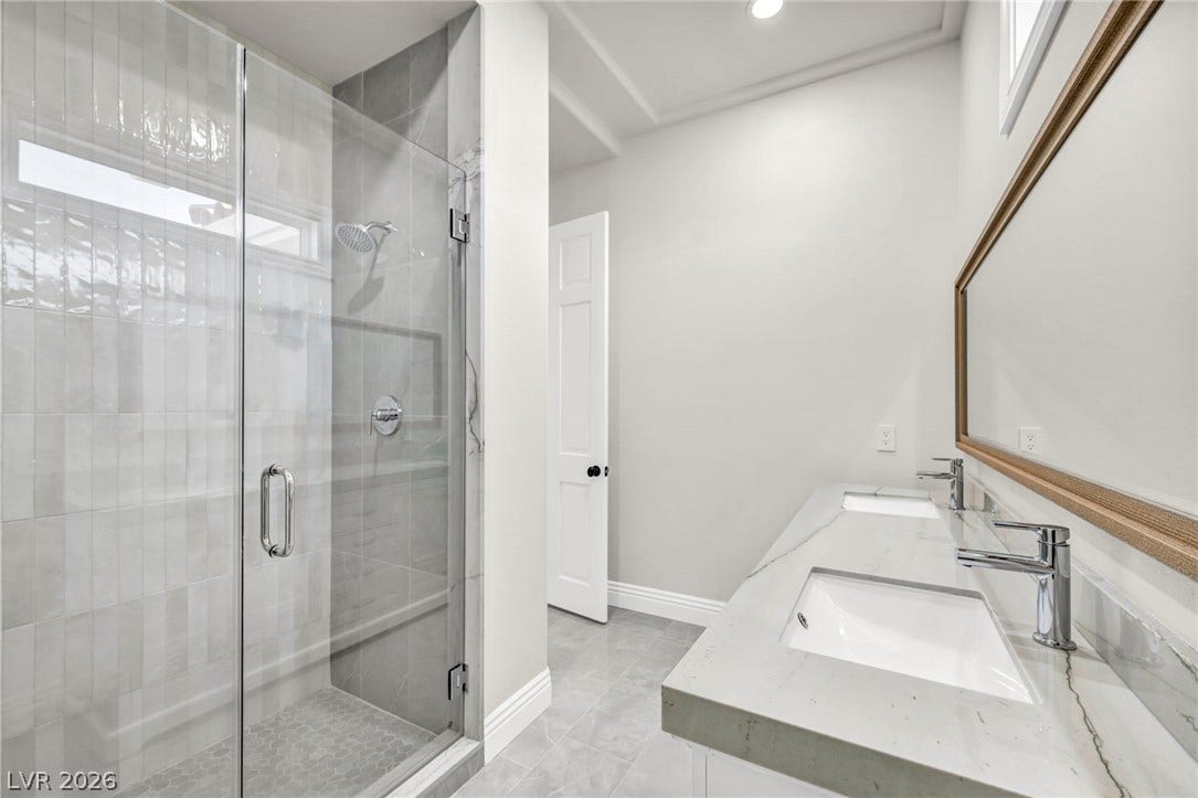 8805 Spanish Mountain Drive, Las Vegas, NV 89148 Clean lines and a spacious dual vanity define this modern, beautifully tiled bathroom.