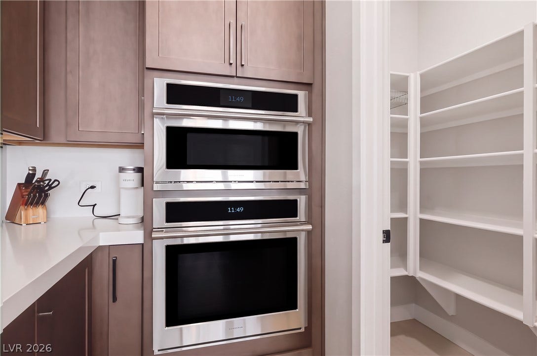 A walk-in pantry provides generous storage adjacent to built-in ovens and clean countertops.